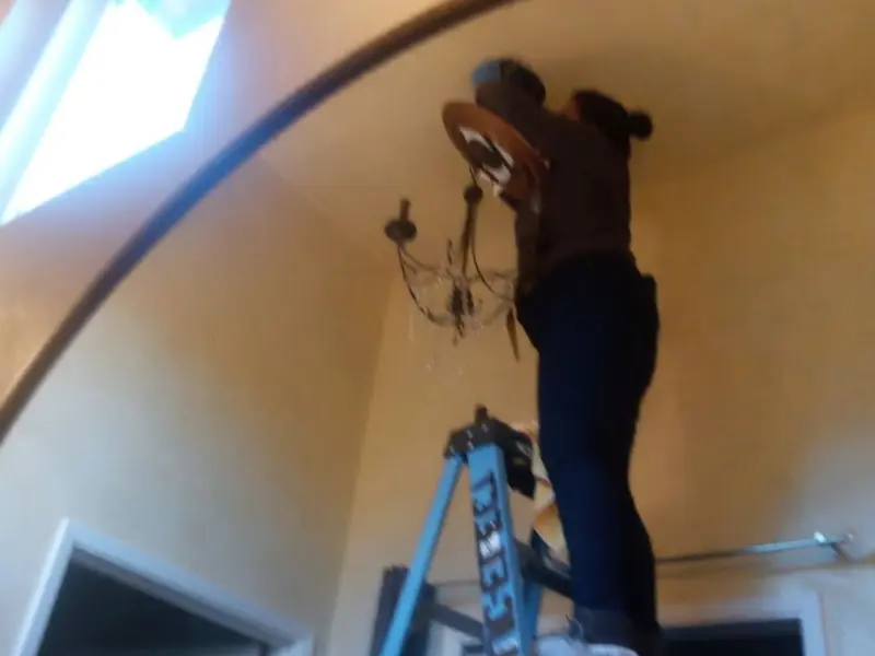 Electrician installing a chandelier in a Alexandria residence